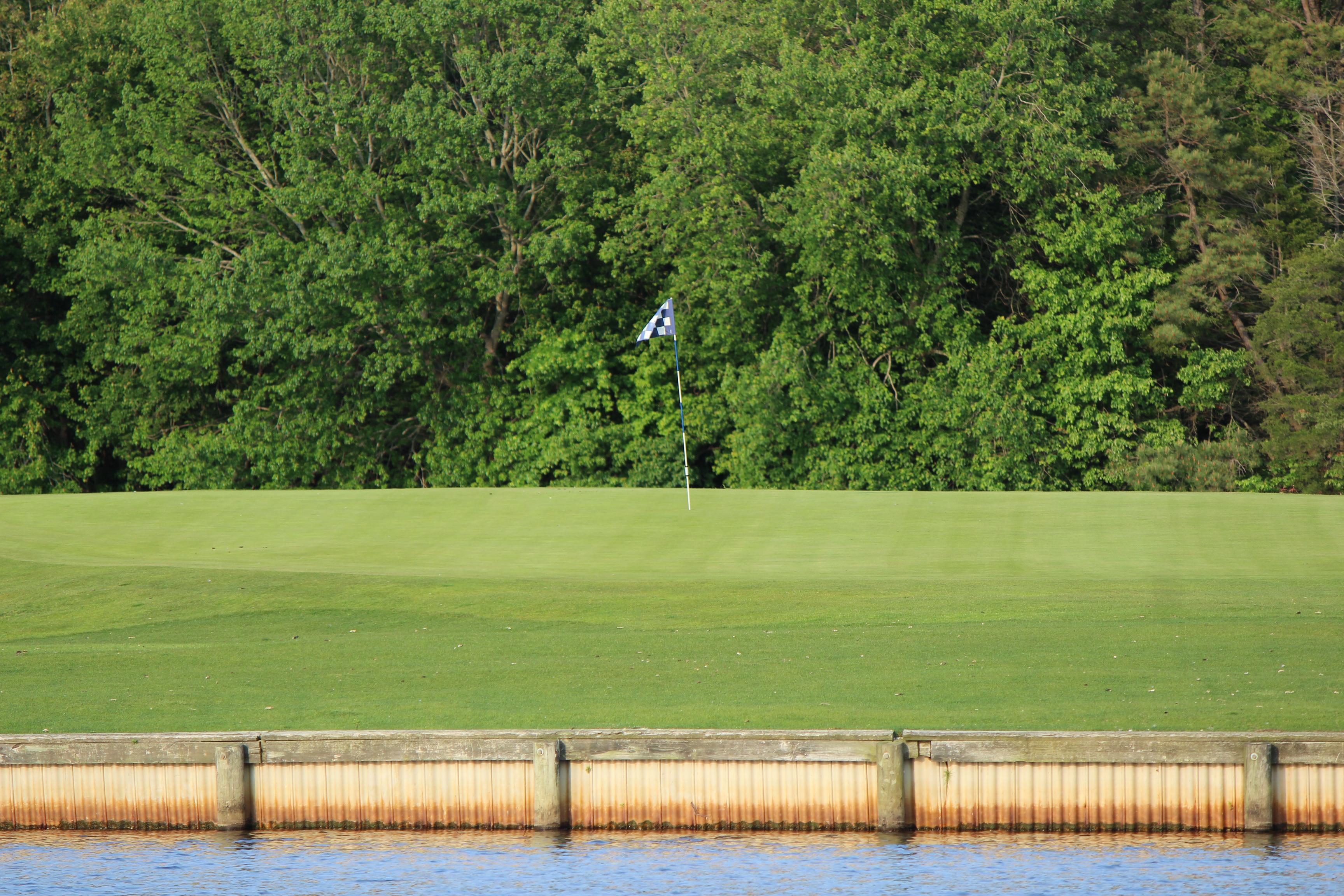 On the 10th Hole, the blue and white checkered flag is positioned in the center of the green. Holiday Lake runs up against the bulkhead that surrounds the green complex.