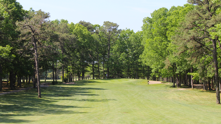 Approach from the fairway to the par 4 17th hole at Ocean Acres Country Club. Oak and pine trees draw the treeline down the fairway and the back of the green.