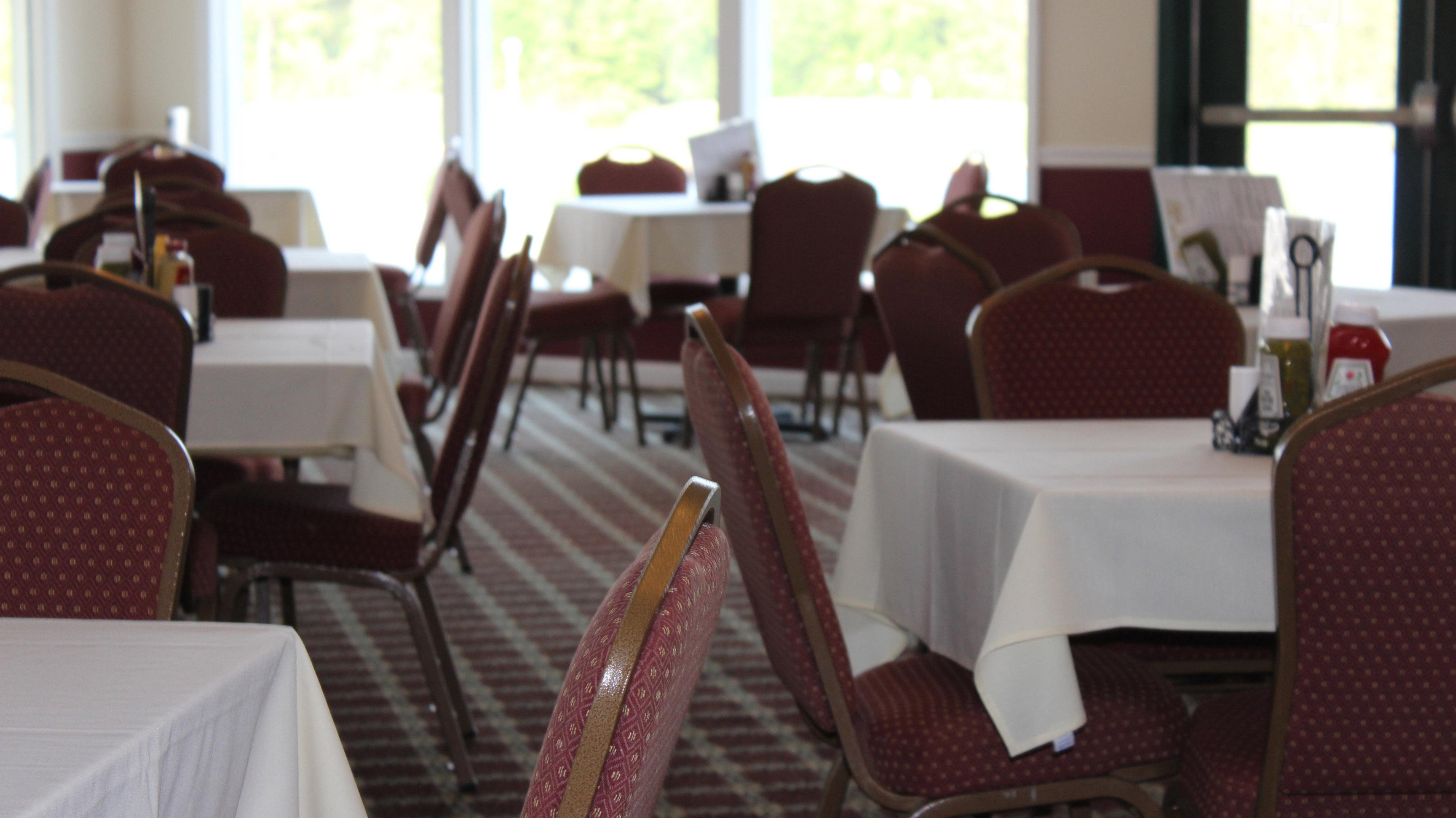 A close up view of dining tables and chairs. The chairs in the background are blurred for graphical effect and the windows can be seen.