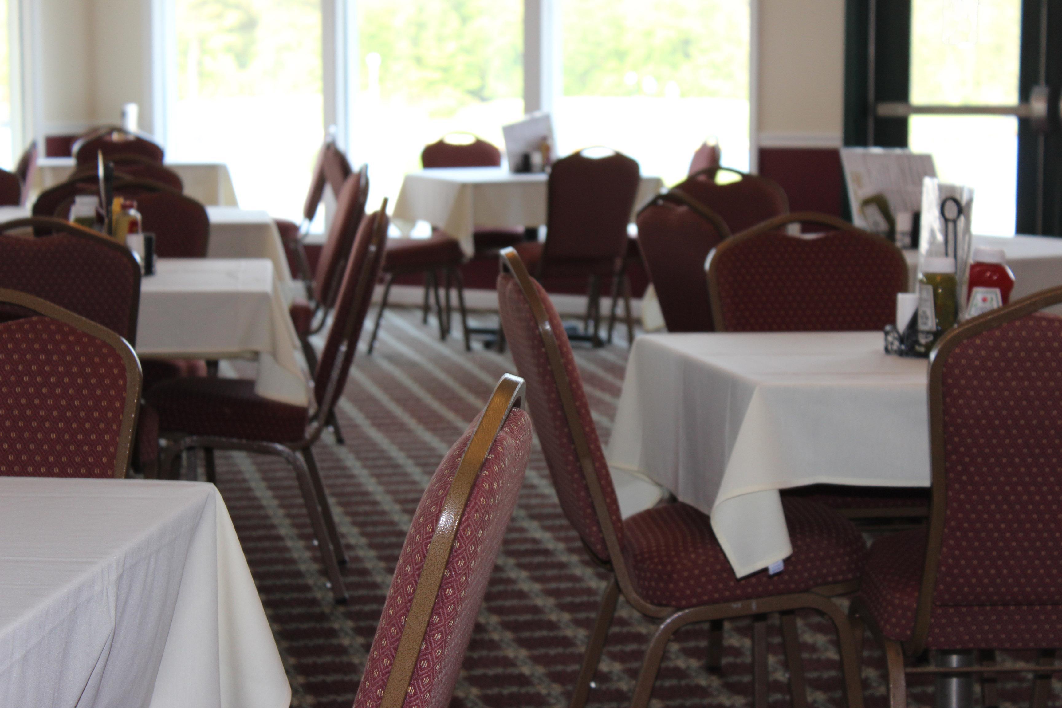 A close up view of dining tables and chairs in The Bunker restaurant. The chairs in the background are blurred for graphical effect and the windows can be seen.